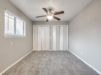 an empty bedroom with a ceiling fan and a window at Diamond Ridge Townhomes, Oklahoma City, 73114